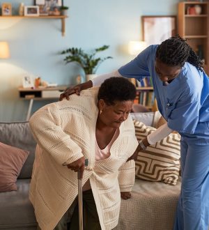 woman-helping-senior-woman-stand-from-couch-2026-01-11-10-30-29-utc